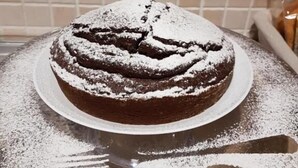 Un gâteau rond, posé sur une assiette, recouvert de sucre glace, est placé sur une table.