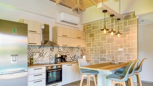 A modern kitchen with a wooden island, bar stools, and a stone backsplash. - Villa Elenitsa - Two Bedroom Villa, Sleeps 4 (Minoa Pediada)