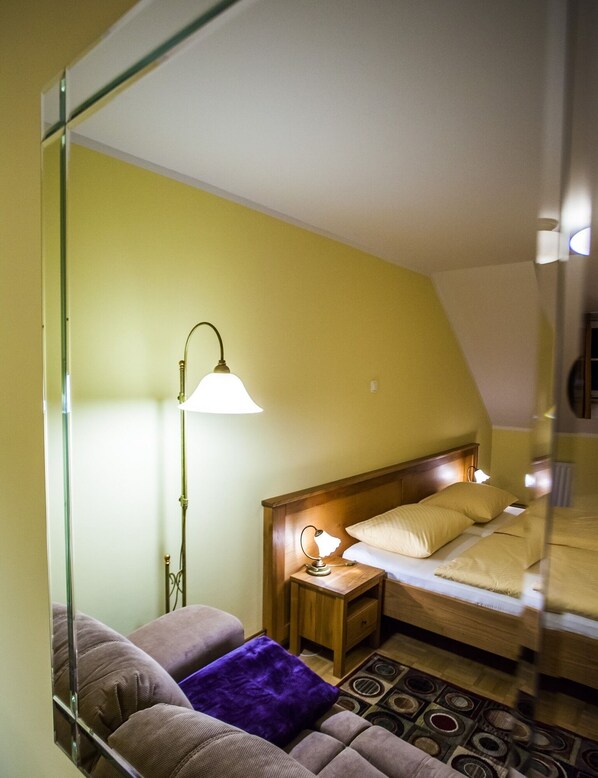 A room with a bed, a nightstand, a lamp, a sofa, and a patterned rug. - B&B Šilak (Ptuj)
