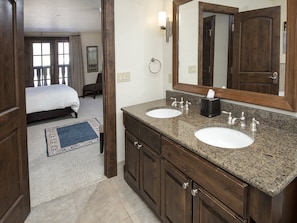 Un baño de hotel con dos lavamanos, un espejo grande y un mueble de tocador de madera.