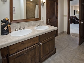 Un baño con tocador de doble lavabo, muebles de madera y un espejo grande.