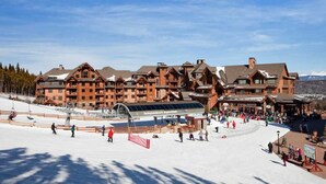 Una stazione sciistica con un ampio chalet a più piani e una seggiovia in primo piano.