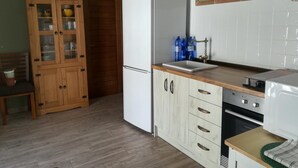 Une cuisine avec des meubles de rangement en bois, un réfrigérateur blanc, un évier et une cuisinière.