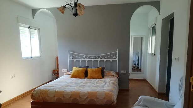 Une chambre à coucher avec un lit, une chaise, un lustre et un miroir.