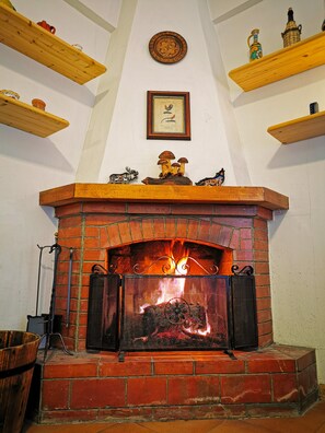 Ein Kamin mit Backsteinverkleidung und einem Metallsieb, der von Holzregalen mit Dekorationen gesäumt wird.