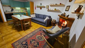 En hyggelig stue med pejs, spiseområde og et køkken.