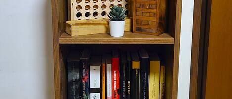 A wooden bookshelf with multiple shelves, some containing books and others with decorative items like a small potted plant and a wooden block.