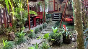 A tropical garden with a wooden bench, a swing, and a stone pathway. - Villa 4 - Amazing 2 Bed Villa with Private Garden, Playa Chiquita (Limón)