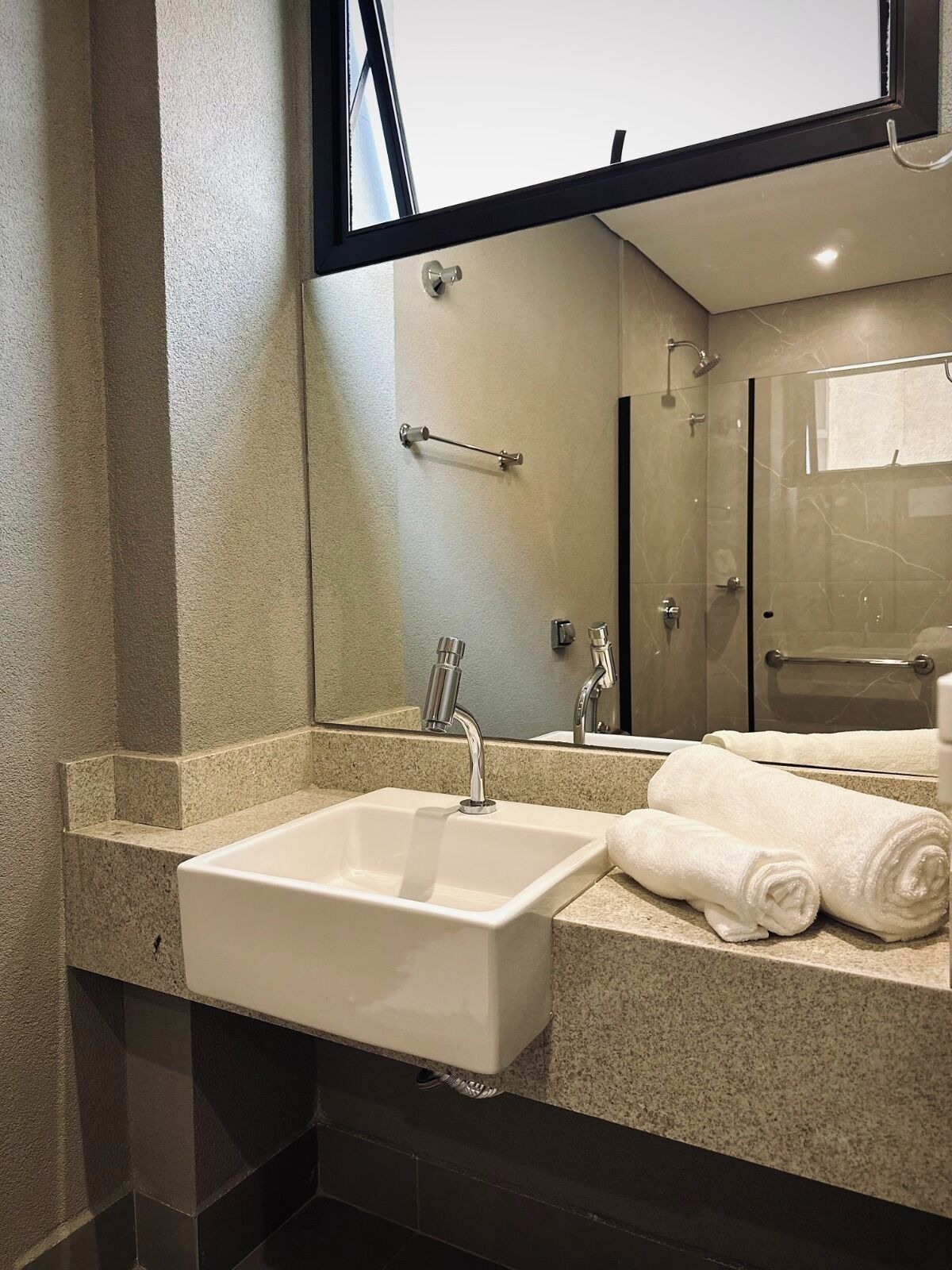A modern bathroom with a large mirror, a sink, and a shower.