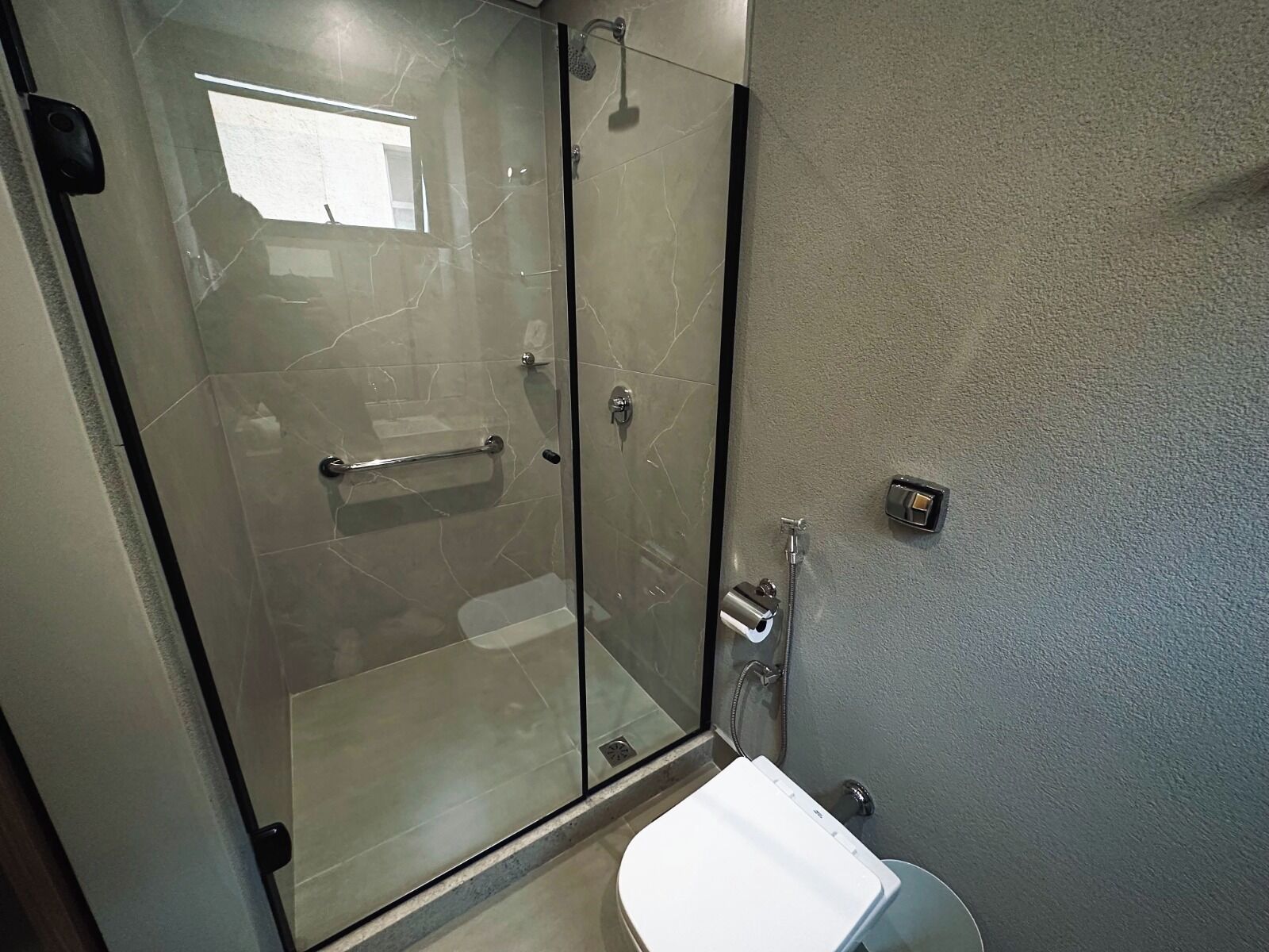 Un bagno moderno con cabina doccia in vetro, un lavabo bianco e un porta asciugamani.