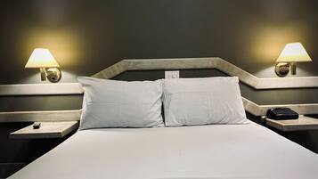 A hotel room with a large bed, two bedside tables, two lamps, and a telephone on one of the tables.