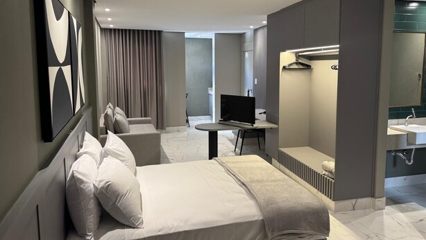 Een moderne hotelkamer met een bed, een televisie, een bureau en een badkamer.