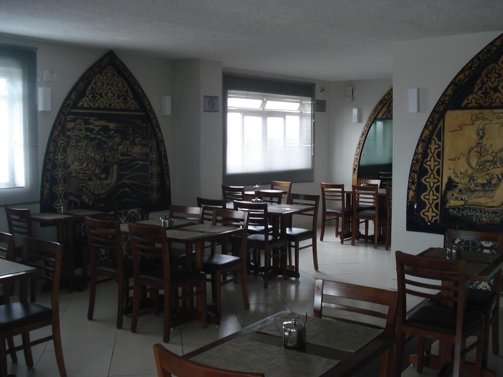 A restaurant with multiple tables and chairs, large windows, and decorative wall art.