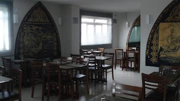 A restaurant with multiple tables and chairs, large windows, and decorative wall art.