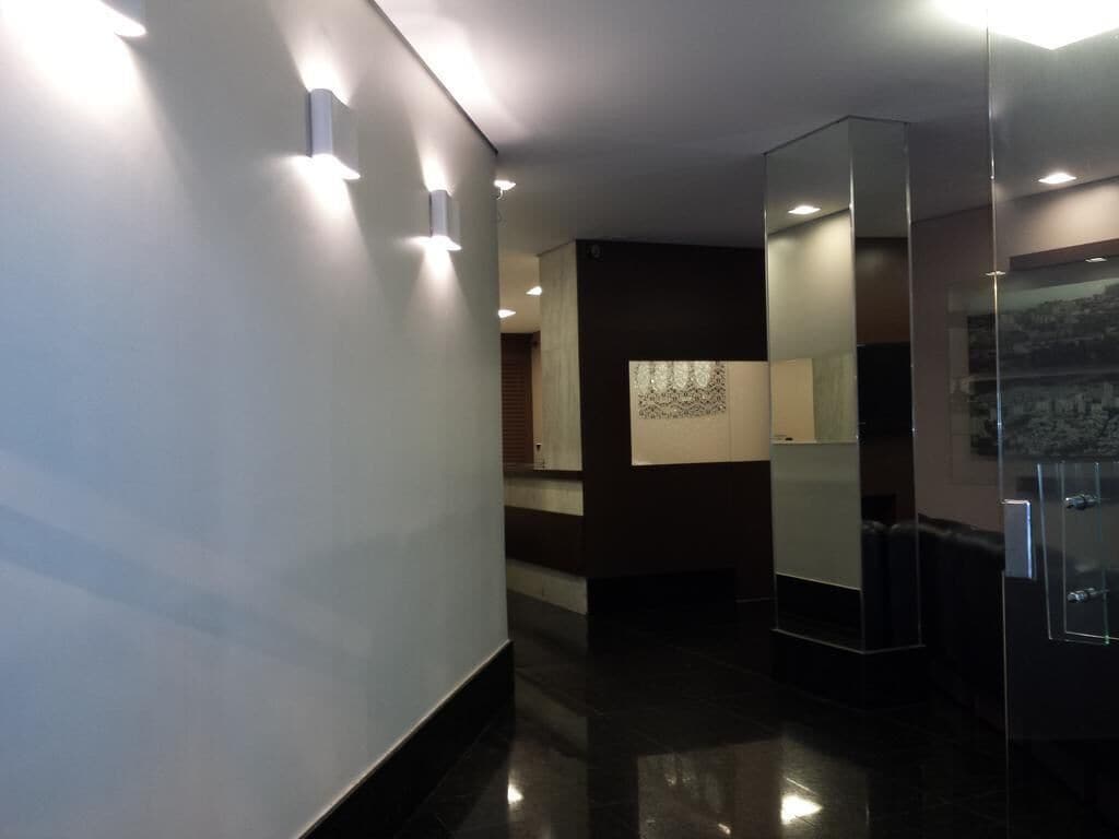 A modern hallway with recessed lighting, a glass partition, and a view of a cityscape through a window.