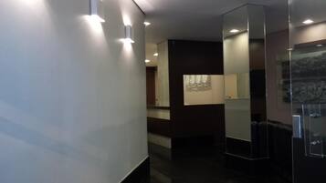 A modern hallway with recessed lighting, a glass partition, and a view of a cityscape through a window.