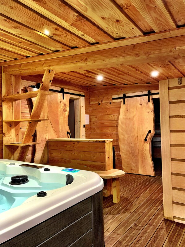 A wooden cabin interior with a hot tub, wooden walls, and a bench. - Luxurious mountain chalet with jacuzzi and sauna (La Bresse)