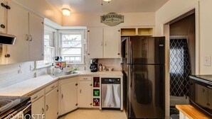 Una cucina moderna con pensili bianchi, un frigorifero in acciaio inossidabile, una macchina per il caffè e una lavastoviglie.