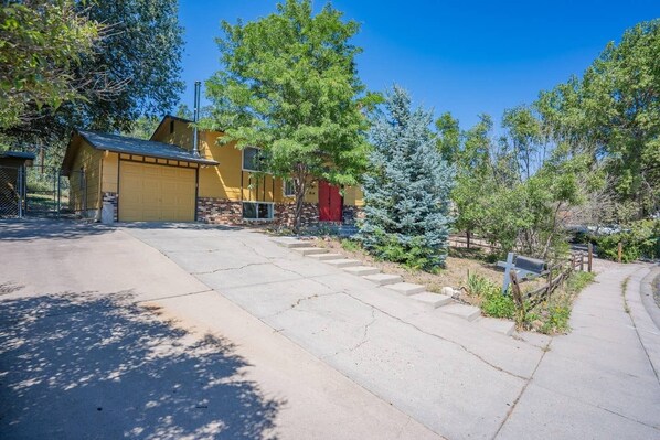 A residential area with a yellow house, a red door, and a staircase leading to a porch. - 4BR Dog-friendly Minutes to Garden of the Gods (Colorado Springs)