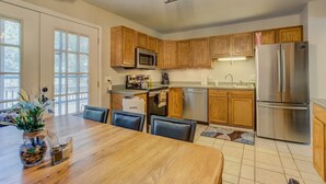 A modern kitchen with wooden cabinets, stainless steel appliances, and a dining area with a wooden table and chairs.