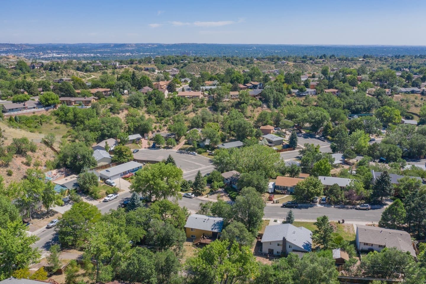 An aerial view of a residential area with houses, roads, and greenery.