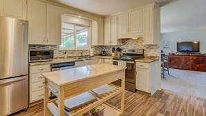 A modern kitchen with stainless steel appliances, a wooden island, and a view into the living area. - 5BR Garden of the Gods is Across the Street! (Colorado Springs)