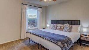 A bedroom with a bed, a ceiling fan, a window with curtains, and a nightstand with a lamp. - 5BR Garden of the Gods is Across the Street! (Colorado Springs)