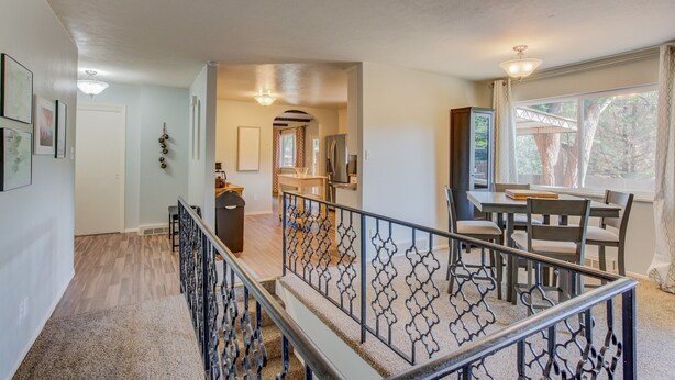 A spacious living area with a staircase, a dining area with a table and chairs, and a kitchen with modern appliances. - 5BR Garden of the Gods is Across the Street! (Colorado Springs)