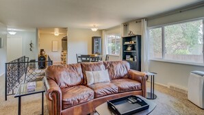 A spacious living room with a leather sofa, a dining area, and a large window providing natural light. - 5BR Garden of the Gods is Across the Street! (Colorado Springs)