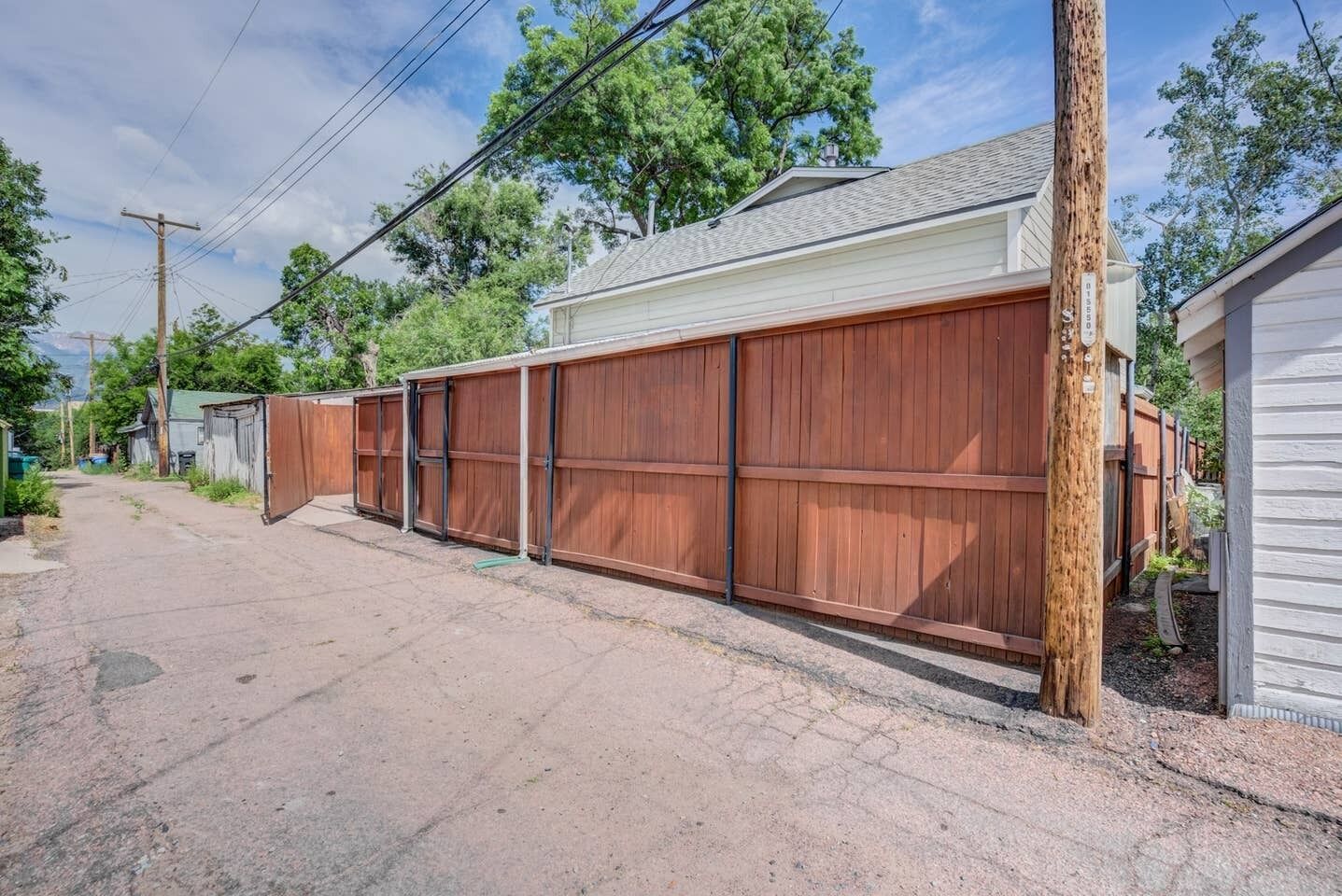 A residential area with a long wooden fence, a garage, and a house with a sloped roof.
