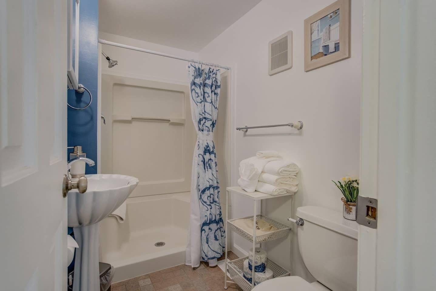 Baño con ducha, inodoro, lavabo y toallero.