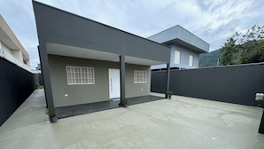 Un bâtiment moderne doté d’un toit plat, d’un patio couvert et d’un petit jardin.