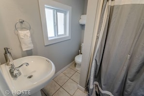 A bathroom with a sink, a window, a toilet, and a shower curtain. - 3BR Of Downtown King Bed, Dining, Has It All! (Colorado Springs)