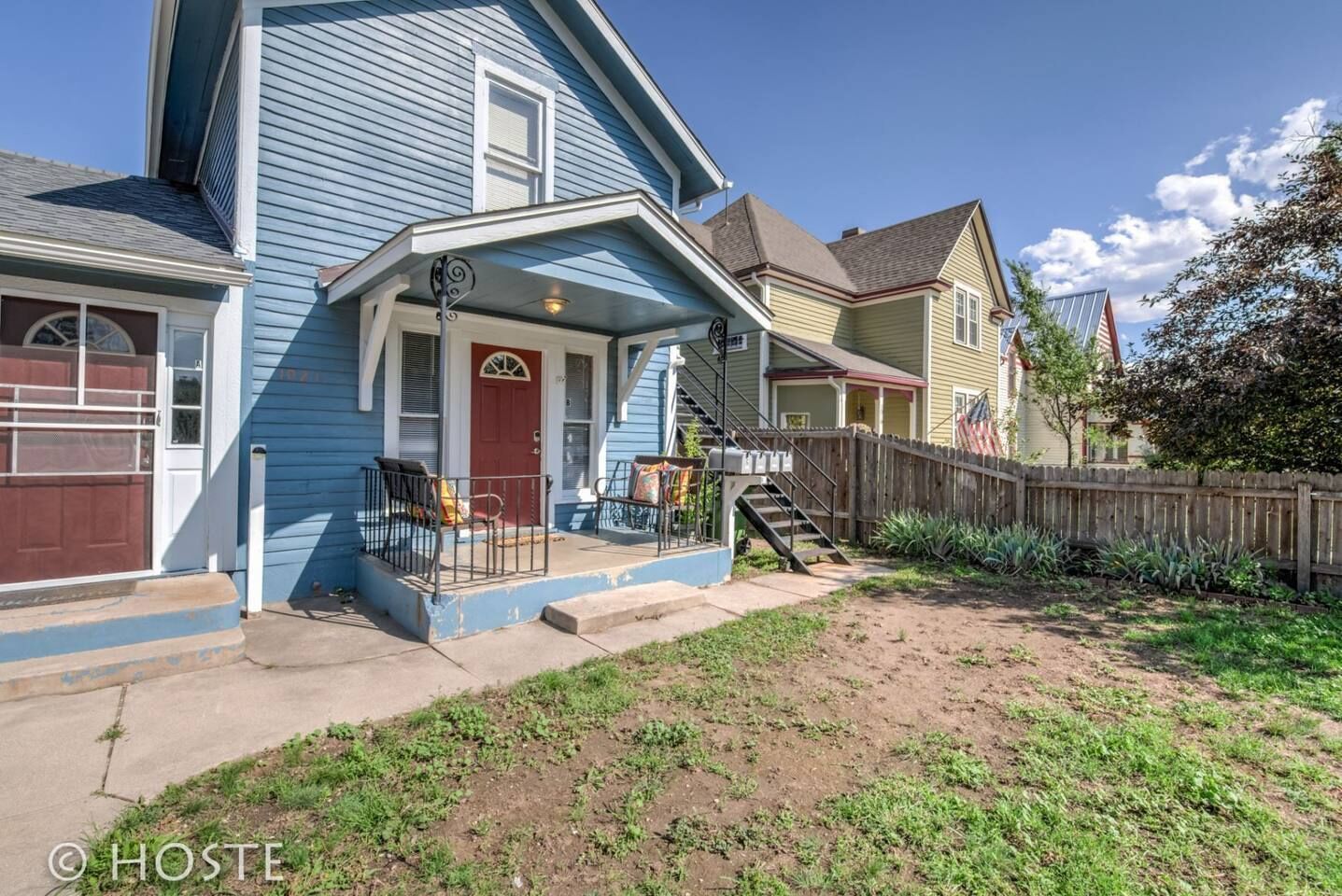 A residential house with a front porch, a staircase leading to the entrance, and a wooden fence.