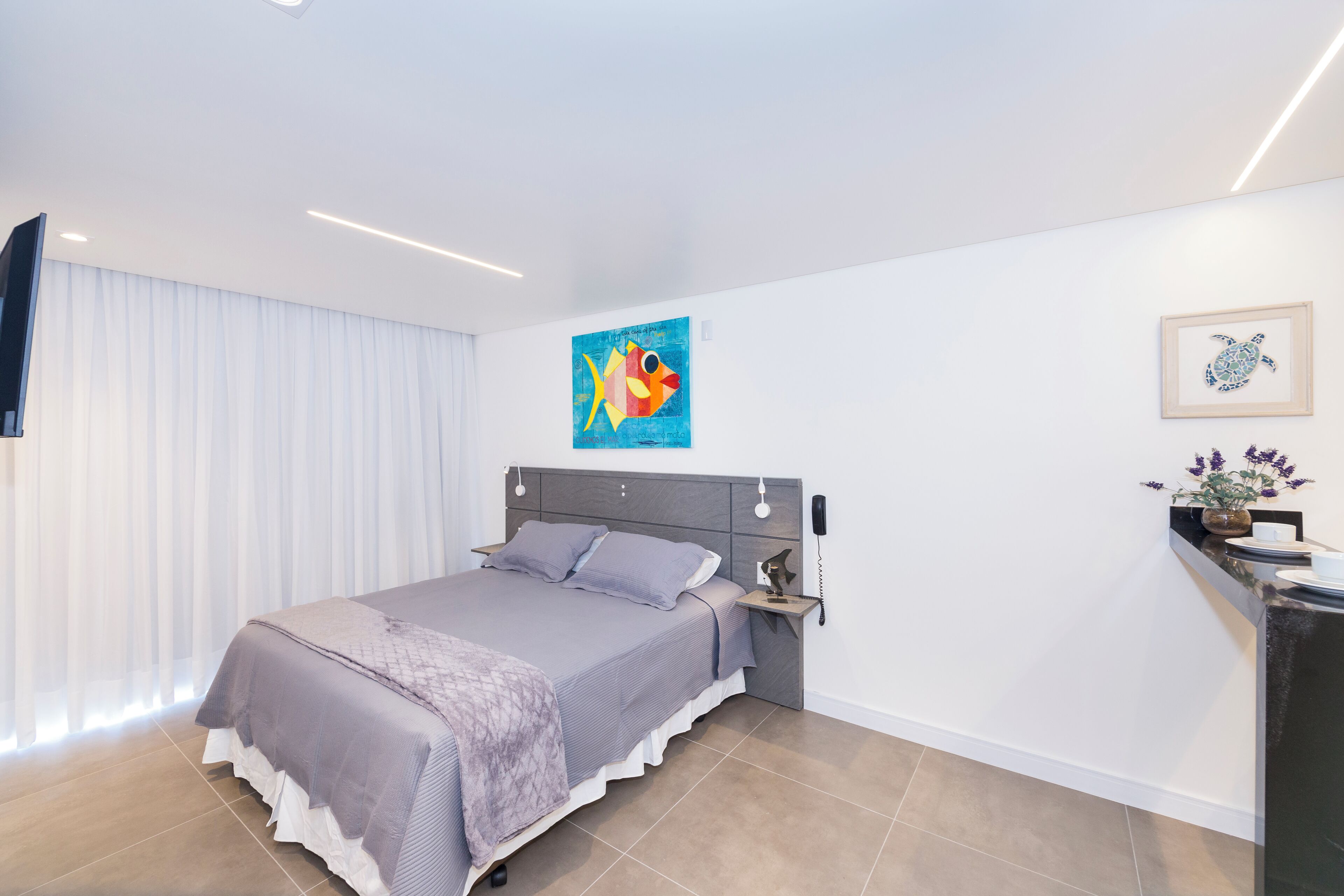 A modern bedroom with a bed, bedside table, and artwork on the wall.
