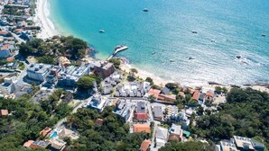 An aerial view of a coastal town with a beach, buildings, and boats. - pousada solar das tartarugas (Bombinhas)