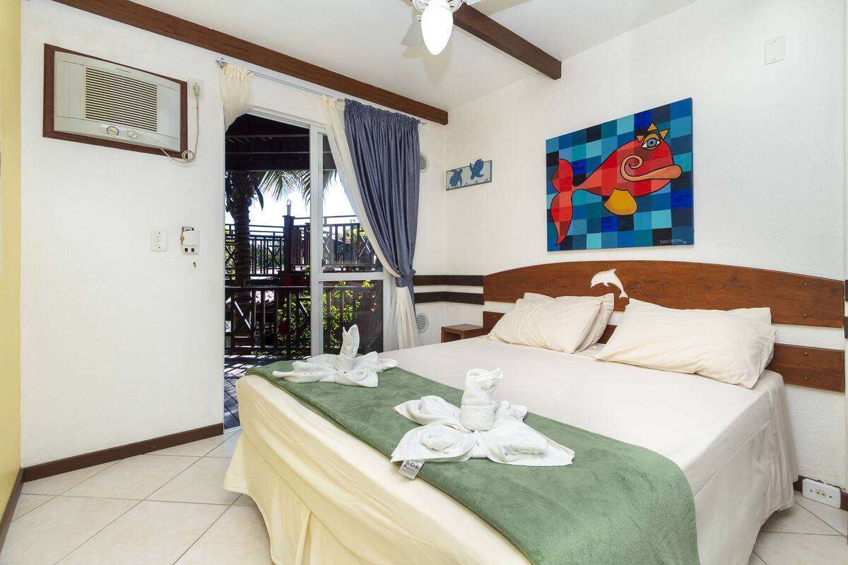 Une chambre d’hôtel avec un lit, une serviette verte et un tableau accroché au mur.
