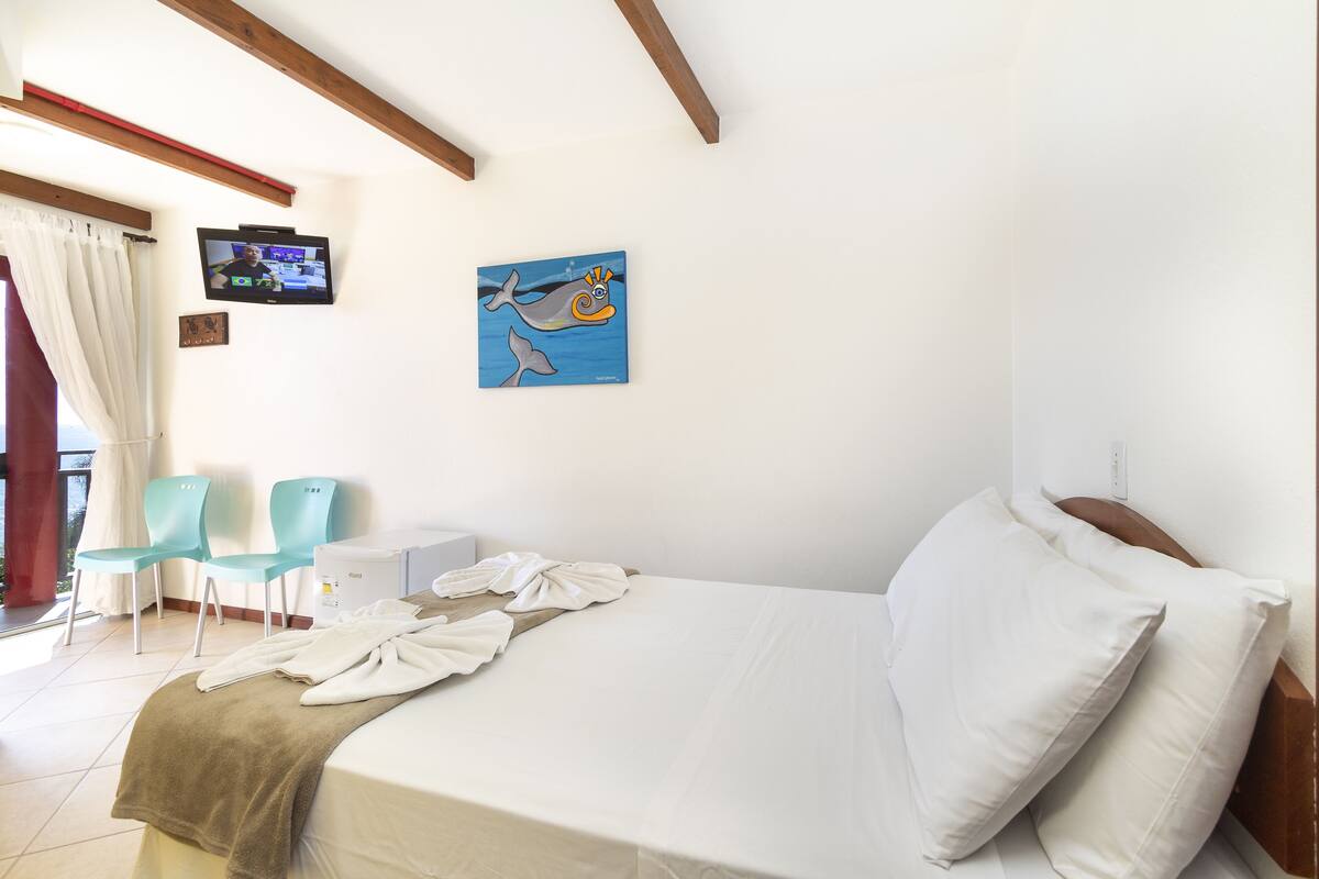 Une chambre d’hôtel avec un lit, deux chaises, une télévision et un tableau représentant un dauphin.