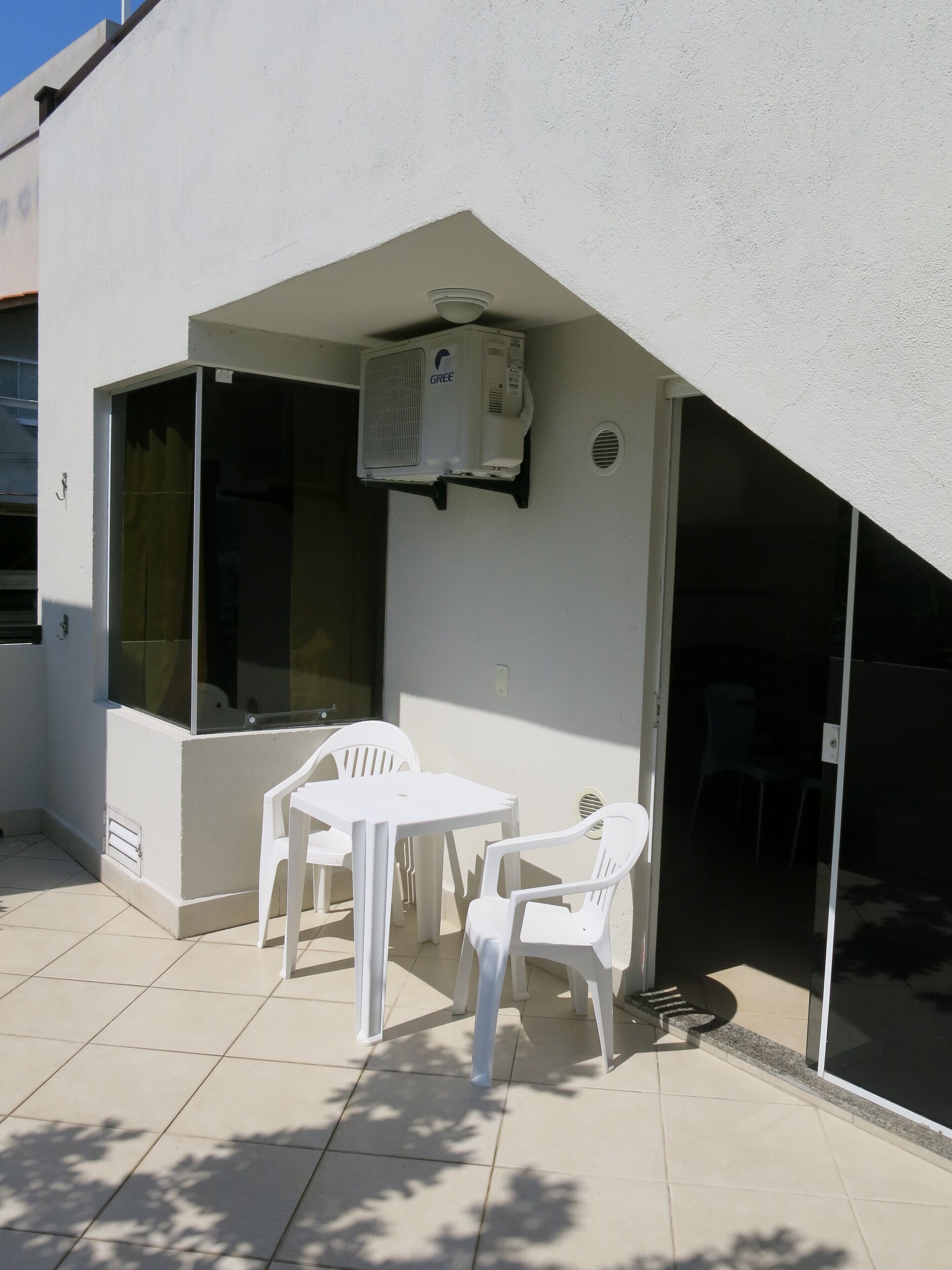 Un pequeño patio al aire libre con una mesa y dos sillas, un ventilador de techo y una ventana.