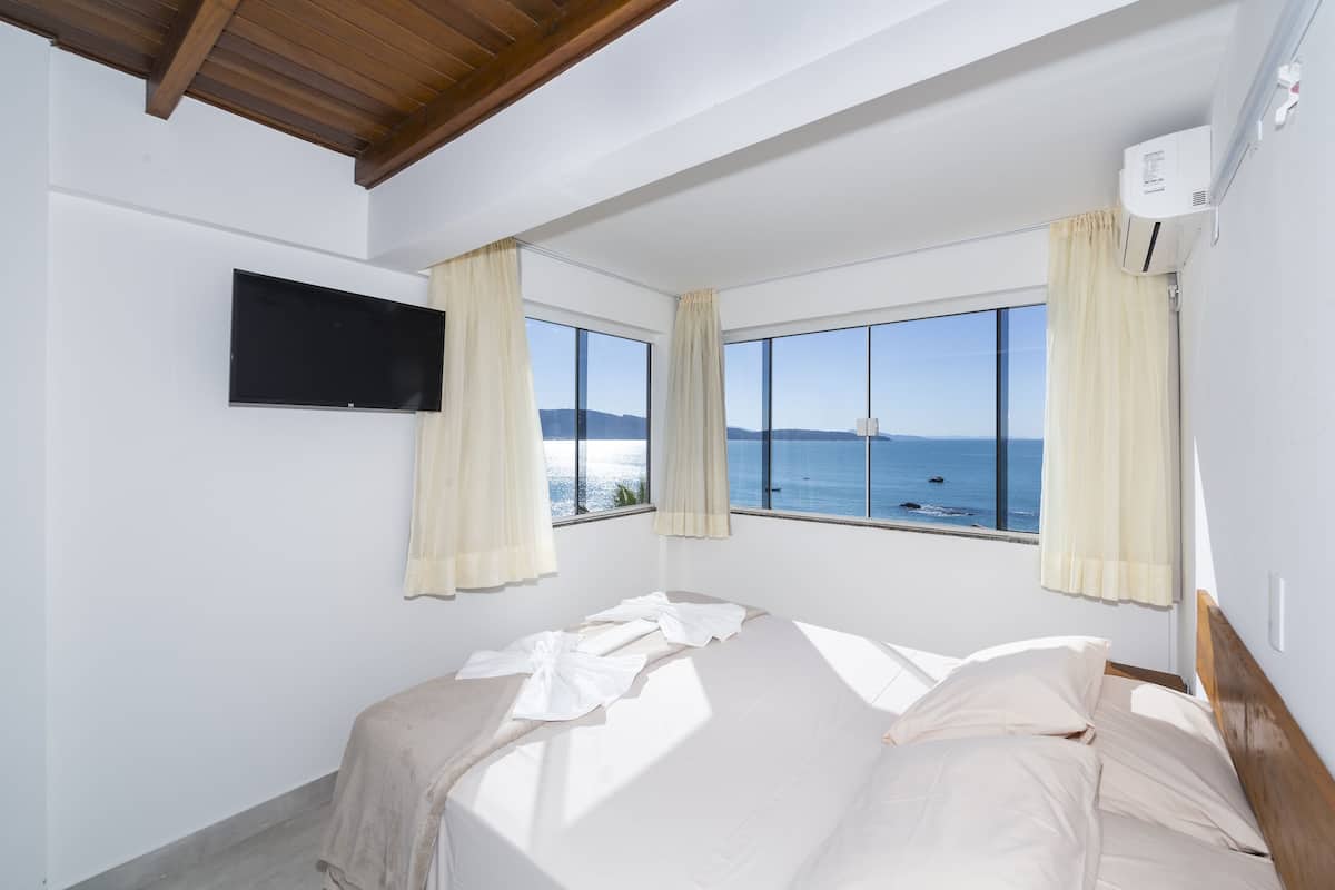 Une chambre à coucher avec un lit, une télévision et de grandes fenêtres avec des rideaux.