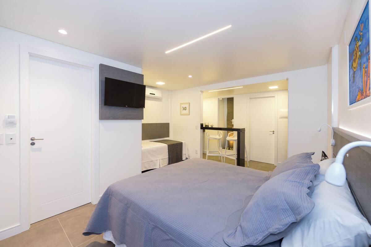 Une chambre moderne avec un grand lit, un téléviseur fixé au mur et un petit espace bureau.