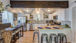 A modern kitchen with white cabinets, a central island with stools, stainless steel appliances, and a dark ceiling. - 2brcheyenne Cañon Minutes to Hiking and Zoo (Colorado Springs)