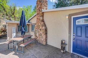 A building with a stone chimney, a blue door, and a picnic table with an umbrella. - 2brcheyenne Cañon Minutes to Hiking and Zoo (Colorado Springs)