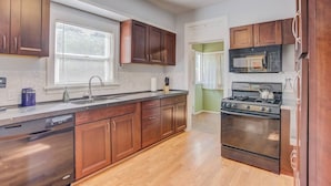 A kitchen with wooden cabinets, a stainless steel sink, a built-in oven, and a microwave.