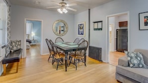 A dining area with a round table, chairs, a ceiling fan, and a mirror on the wall.