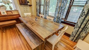 A wooden dining table with benches, white chairs, and a piano in the background. - 4BR Dog Friendly Mtn Retreat With Gym! (Colorado Springs)