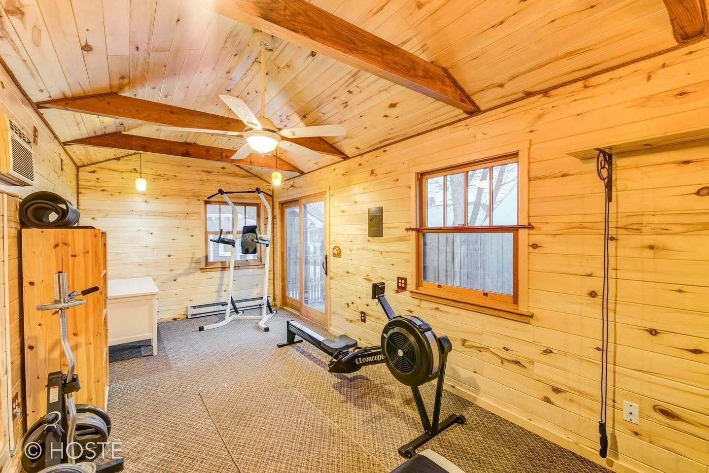 A wooden cabin with a gym area including a treadmill, weight bench, and exercise equipment.