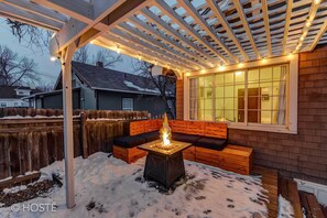Un espacio cubierto con un hogar para la chimenea, asientos de madera y luces colgantes.