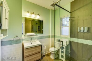 Une salle de bain avec une douche à parois de verre, un lavabo avec un miroir au-dessus et des toilettes.
