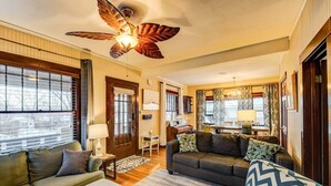 A cozy living room with a wooden ceiling fan, a piano, and a dining area with a chandelier. - 4BR Dog Friendly Mtn Retreat With Gym! (Colorado Springs)